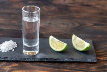 Glass of tequila with lime wedges