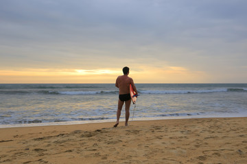 Rear view of surfer with surfboard