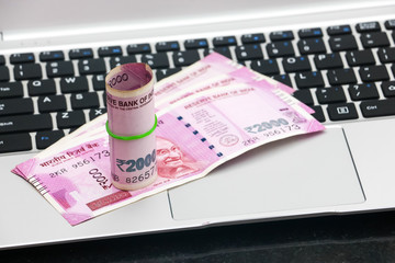 Close up view of brand new indian 2000 rupees banknotes and  laptop.