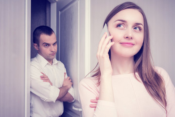 Jealous boyfriend spying on girl, his flirting on the phone with another man, portrait, close up, toned