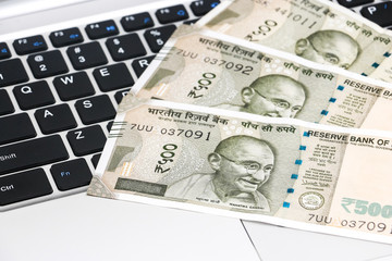 Close up view of brand new indian 500 rupees banknotes and  laptop.