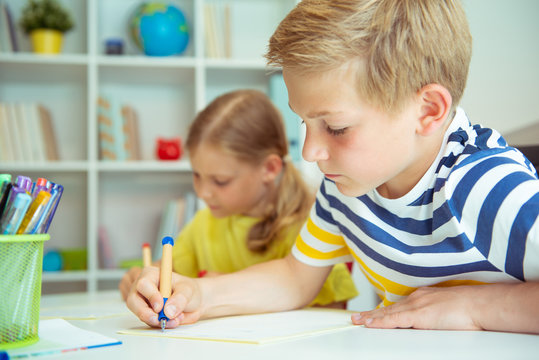 Cute schoolchildren are came back to school and learning at the table in classroom