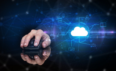 Hand using wireless mouse in a dark environment with cloud technology and online storage concept