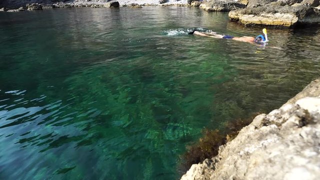 a man dives into crystal clear sea in a mask for snorkeling, removes underwater world on an action camera
