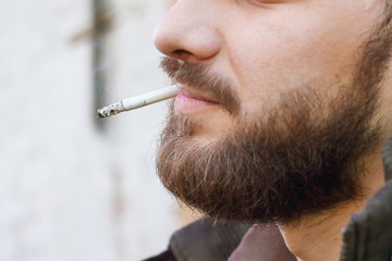 Portrait of brutal hipster adult working man after labor day with a beard close up smoking...