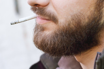 Portrait of brutal hipster adult working man after labor day with a beard close up smoking...