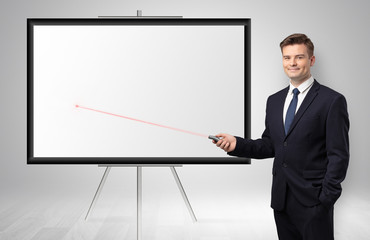 Young businessman with laser pointer and copyspace white wall