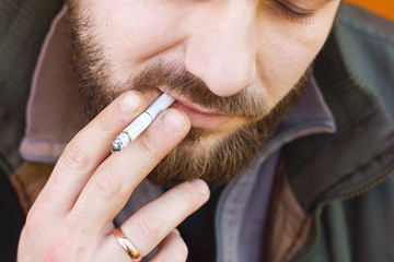 Portrait of brutal hipster adult working man after labor day with a beard close up smoking...