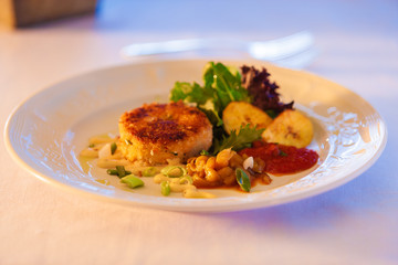 A delicious crab cake on a white plate.