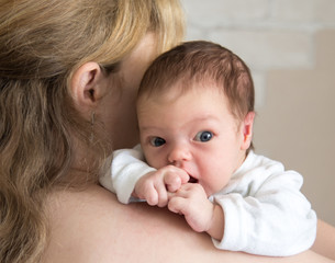 Young woman holds a newborn baby on the shoulder