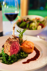 Lamb chops on a white plate with red wine.