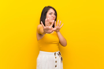 Young Mexican woman over isolated yellow background nervous stretching hands to the front