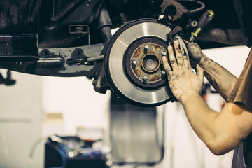 Car mechanic changing car brakes, transportation concept (color toned image)