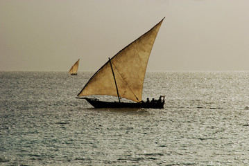 Fototapeta premium Tanzania, Zanzibar, Nungwi, traditional sailing boat on the turquoise Indian Ocean with storm coming in the background
