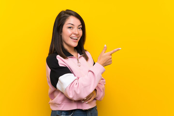 Young Mexican woman over isolated yellow background pointing finger to the side