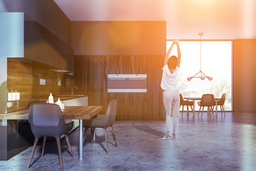 Woman in gray and wooden kitchen with tables