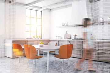Woman walking in white kitchen with orange chairs