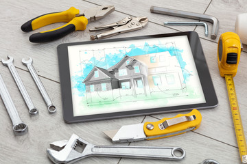 Tablet with construction tools and house plan concept