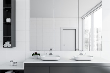 Double sink in white tile bathroom interior