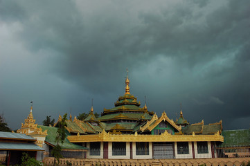 Myanmar, Inle, Buddhist temple with highly decorated sikhara top and a stormy sky