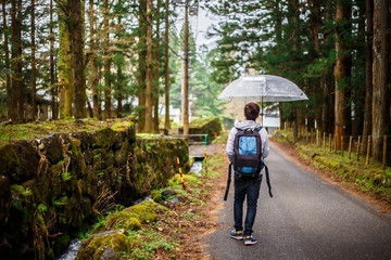 Young man with umbrella in Japan. Walking on the street. vacation concepts.