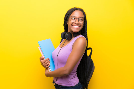 African American Teenager Student Girl With Long Braided Hair Over Isolated Yellow Wall Laughing