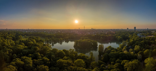 An idyllic park in the Englischer Garten of Munich with a beautiful lake as an aerial. - obrazy, fototapety, plakaty