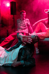 selective focus of man lying on floor in nightclub and covering face