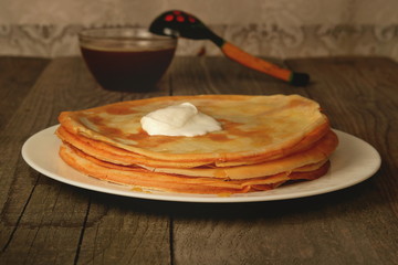 Pancakes with sour cream on a wooden table. Homemade crepes
