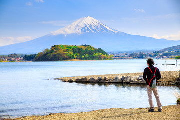 Mt diamond fuji with snow and flower garden along the lake walkway at Kawaguchiko lake in japan, Mt Fuji is one of famous place in Japan. A man stand and looking far away.