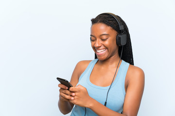 African American teenager girl with long braided hair listening music with a mobile