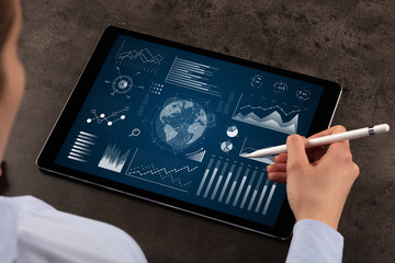 Business woman verifying reports on tablet with pencil in business suit