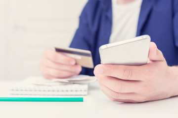 Man uses a smartphone and a plastic card to pay,, close up