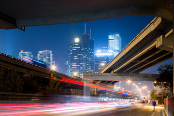 China, Beijing, Highway overpass and glowing steel and glass office towers along Third Ring Road in central business district at night