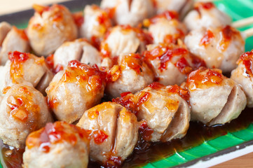 Grilled meat balls with spicy dipping chili sauce serve on green plate.  Popular appetizers side dish roasted meat balls.