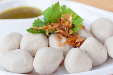 Boiled pork ball appertizer food, pork balls serve on whit plate and celery vegetable leaf, garlic oil and spicy sauce.