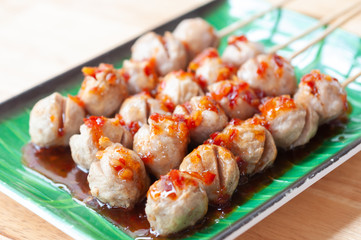 Grilled meat balls with spicy dipping chili sauce serve on green plate.  Popular appetizers side dish roasted meat balls.