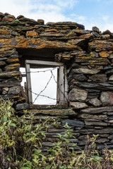 Georgia, Mtskheta, Juta. A window in a stone wall, covered with barbed wire.