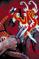 Asia, India, Darjeeling. This trimmer's deft hands and shiny shears perfect a carpet at the Tibetan Refugee Center, Darjeeling, India.