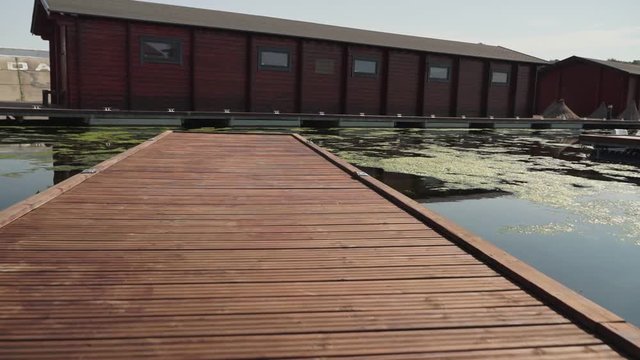 footage of camera moving along long wooden pier in the river at suny light.
