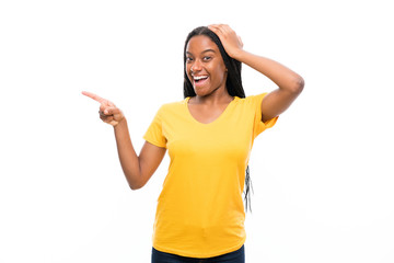 African American teenager girl with long braided hair over isolated white background surprised and pointing finger to the side