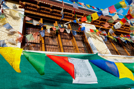 India, Jammu & Kashmir, Ladakh, prayer flags blowing in front of a traditional Ladakh building in downtown Alchi.