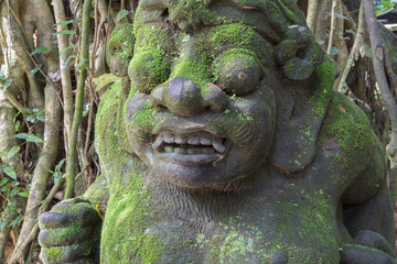 Indonesia, Bali. Temple Statue in the Monkey Forest of Padangtegal, a sacred Balinese Hindu site. Balinese Hinduism combines aspects of Animism, Ancestor Worship, Buddhism, and Hinduism.