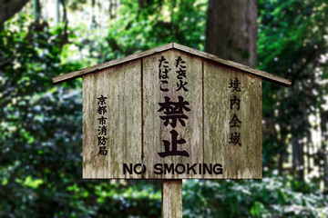 Kyoto, Japan. Wooden no smoking sign written in English and Japanese near wooded area