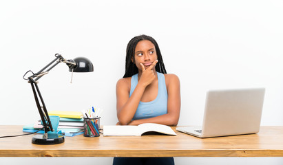 African American teenager student girl with long braided hair in her workplace thinking