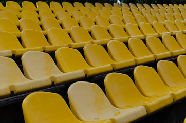 Fototapeta na wymiar Rows of empty plastic yellow chairs at the stadium. Outdoors