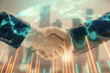 Double exposure of financial chart and world map on cityscape background with two businessmen handshake. Concept of international investment