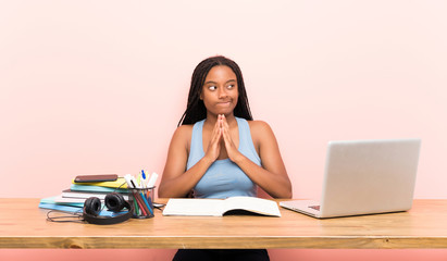 African American teenager student girl with long braided hair in her workplace scheming something