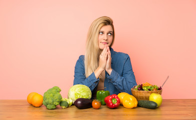 Young blonde woman with many vegetables scheming something