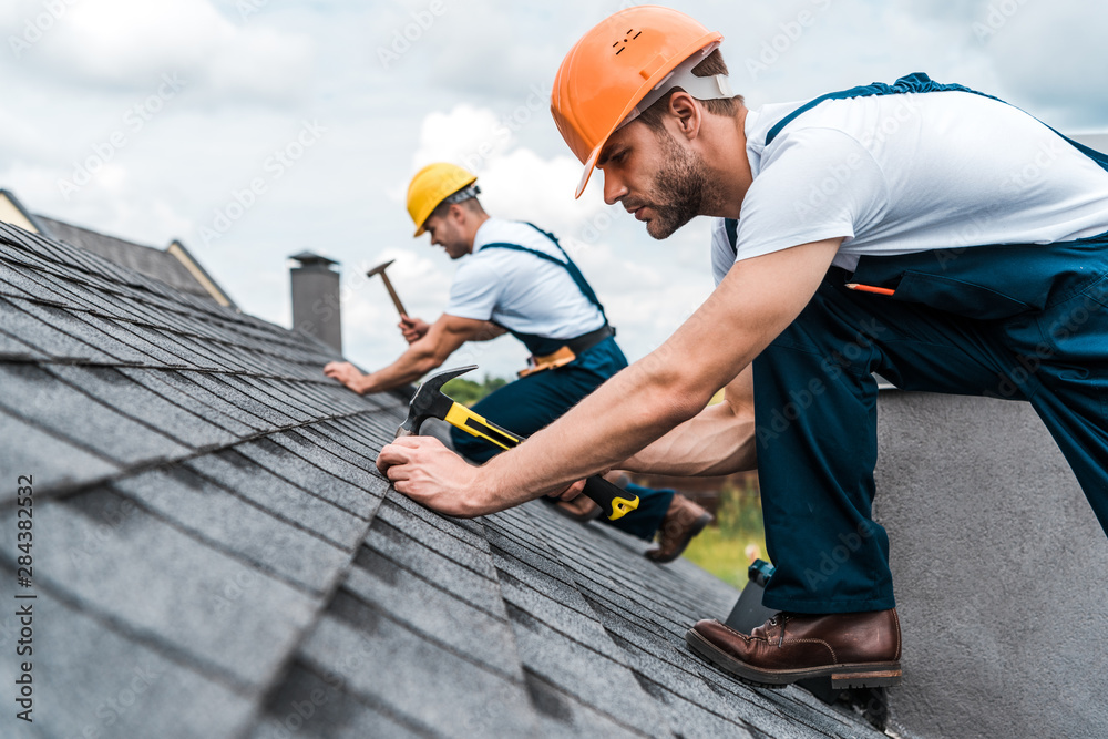 Wall mural selective focus of handsome handyman repairing roof with coworker